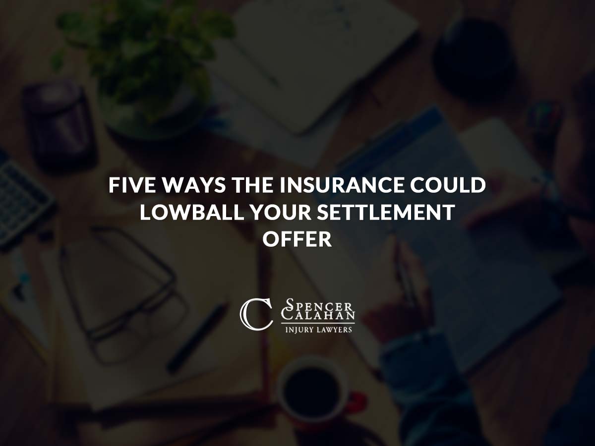 Person looking at scattered documents on table. Text overlay: Five Ways the Insurance Could Lowball Your Settlement Offer