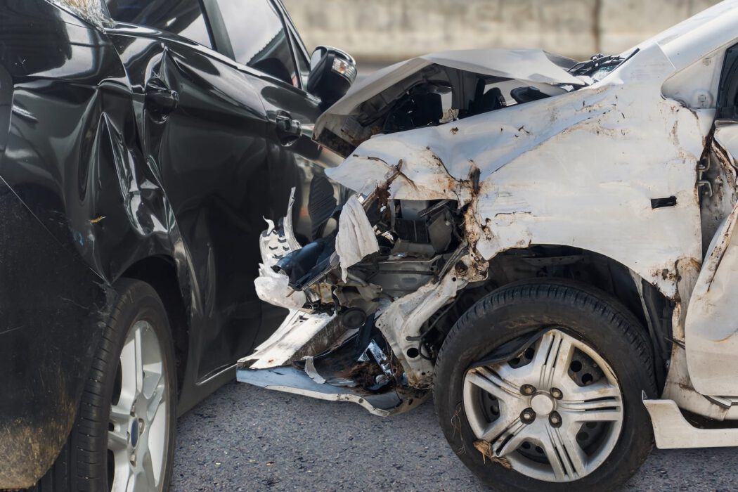 A white car with heavy front-end damage collided with a black car, the type of scene an injury lawyer might evaluate after a crash.